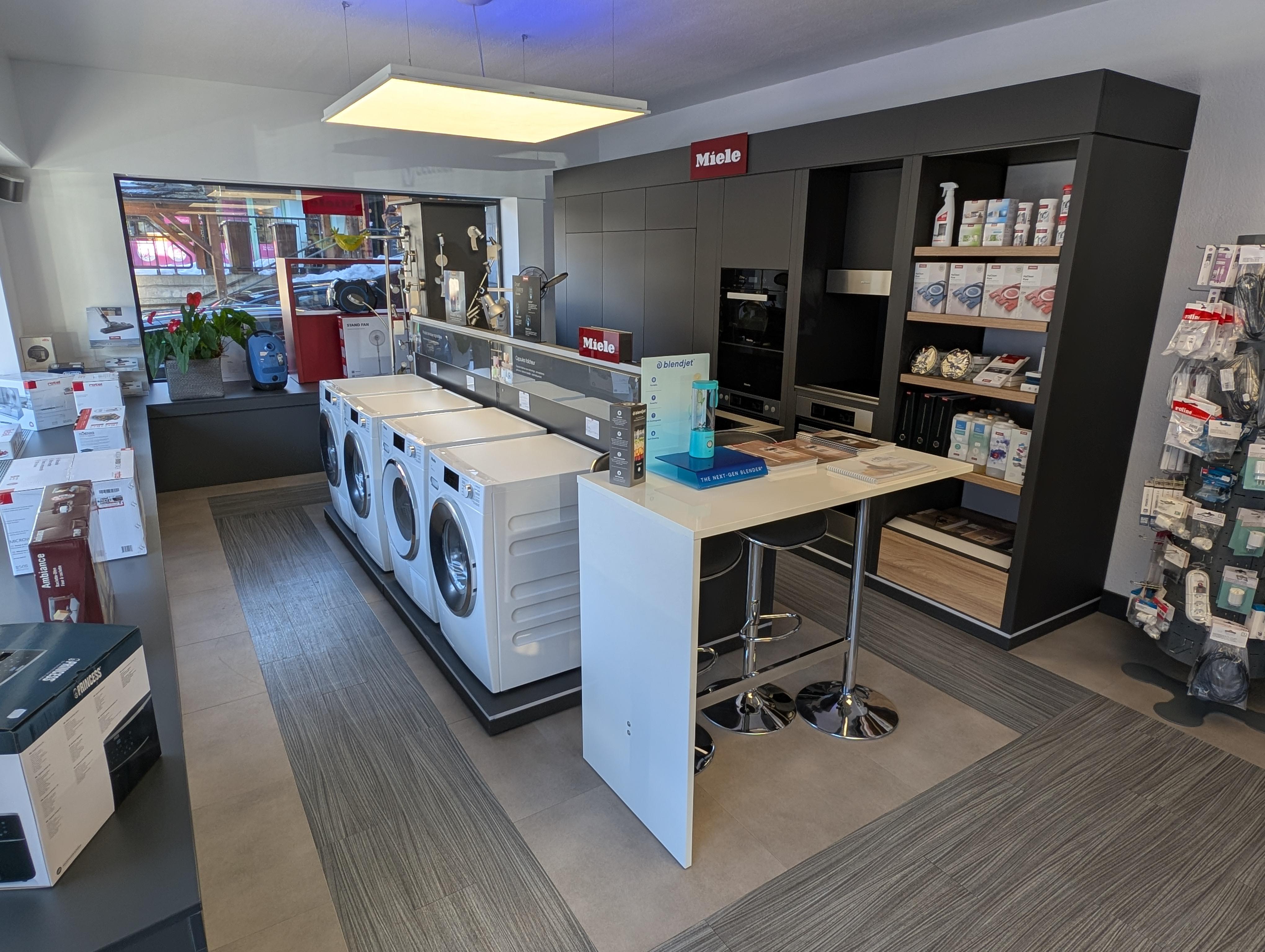 Showroom d'électroménager premium avec machines à café Nespresso et appareils Miele intégrés dans une cuisine contemporaine valaisanne