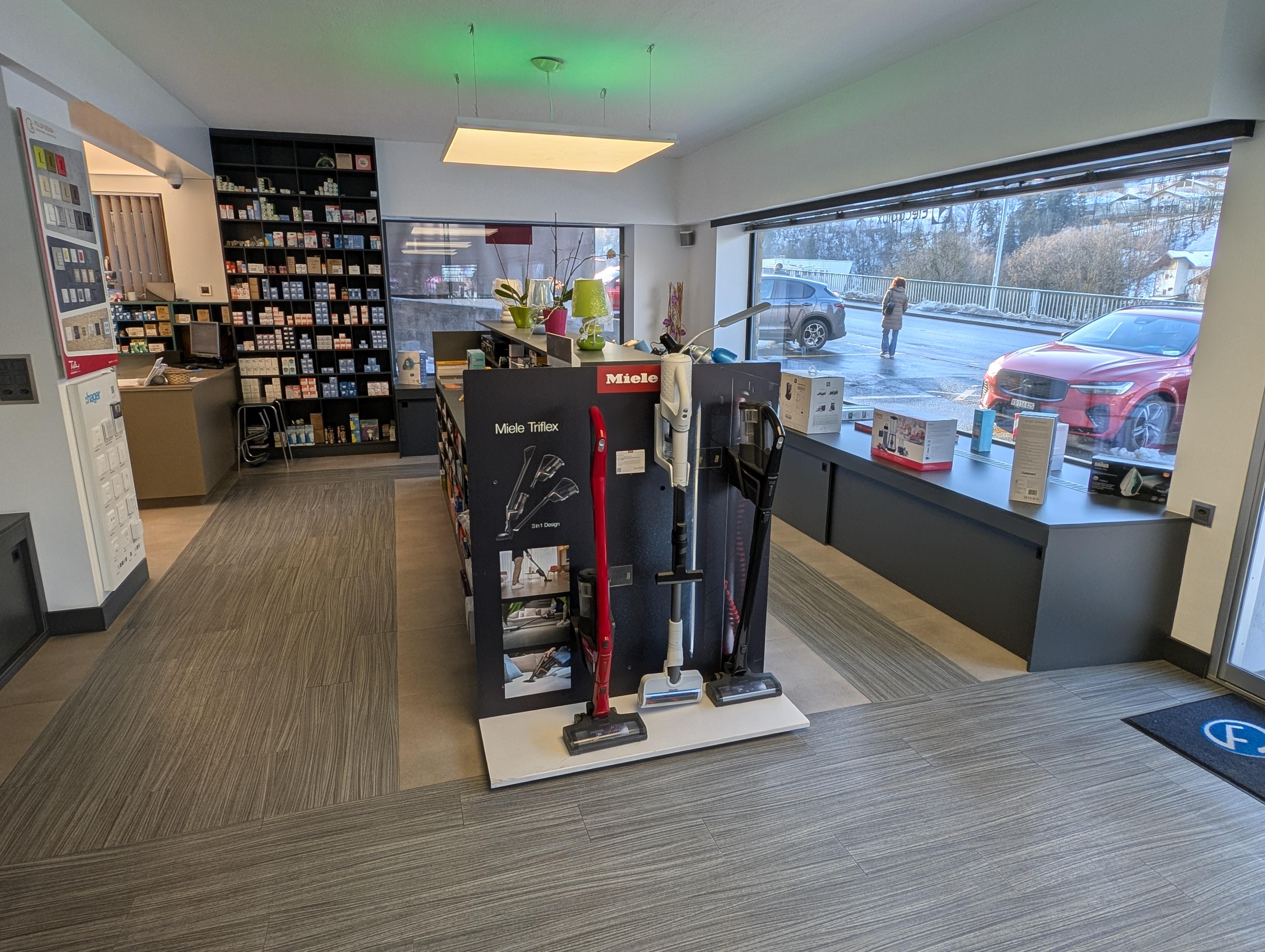 Showroom d'électroménager moderne avec appareils Miele et Nespresso exposés dans un intérieur chaleureux aux tons ardoise et laiton